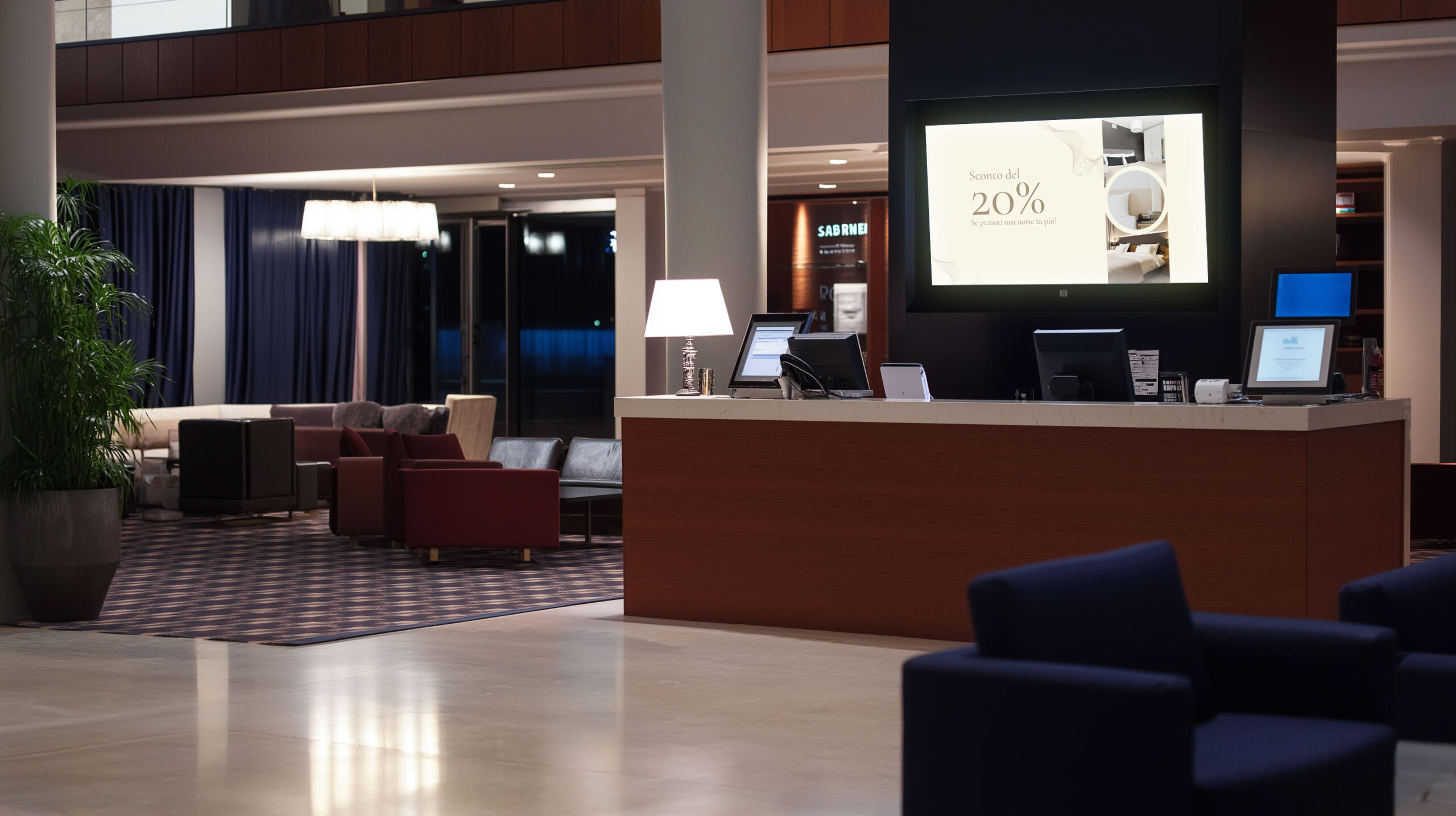 Reception hotel con display che mostra una promozione del 20% per incentivare il soggiorno