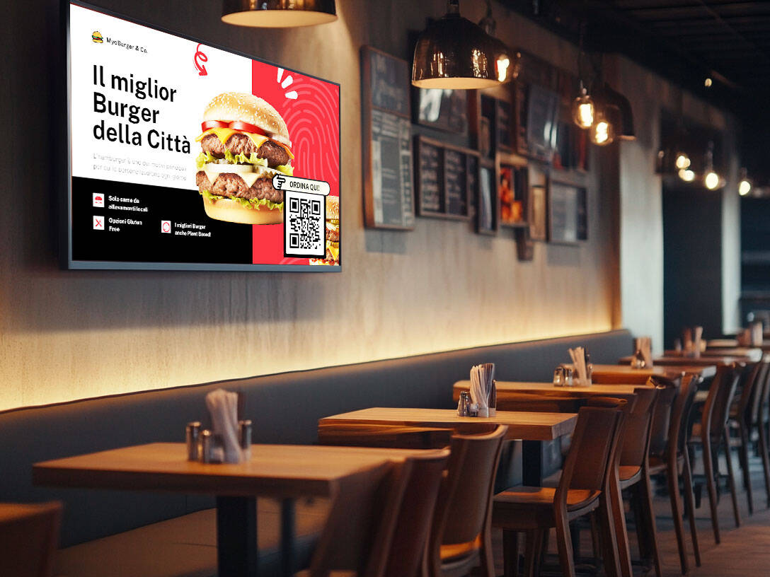 Schermo digitale Esapix che presenta la promozione di un hamburger con QR code per ordinazione diretta, installato in un moderno locale ristorativo.