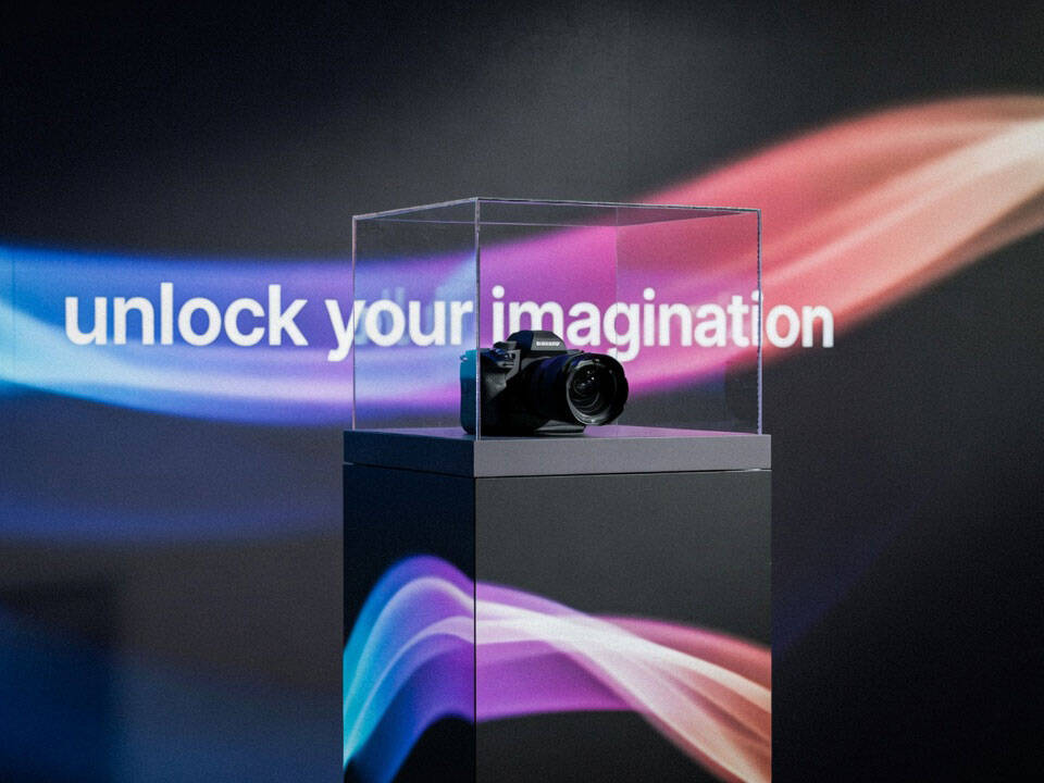 Espositore interattivo con piedistallo e LED wall per prodotto tech. Soluzione Digital Signage Esapix con proiezione immersiva sullo sfondo