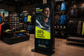 Totem pubblicitario digitale in un negozio di abbigliamento sportivo che promuove una collezione con sconto del 20%.