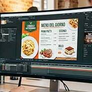 Schermo che mostra monitor in un ufficio creativo Esapix, un creativo prepara un menu digitale.